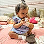 Fatima joined the competition — help win amazing prizes! baby, child, sitting, sock, bed, blanket, pillow, room, indoor, cute, playful, clothing, dress, footwear, person, hair, smile, infant, toddler, toy