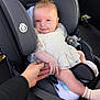 Luna is registered to the contest to win money with this photo: baby, car_seat, child, smiling, holding_hand, lace_dress, infant, safety, seatbelt, cute, car_interior, person, hand, happy, portrait, young_child, clothing, seat, infasecure, baby_sock