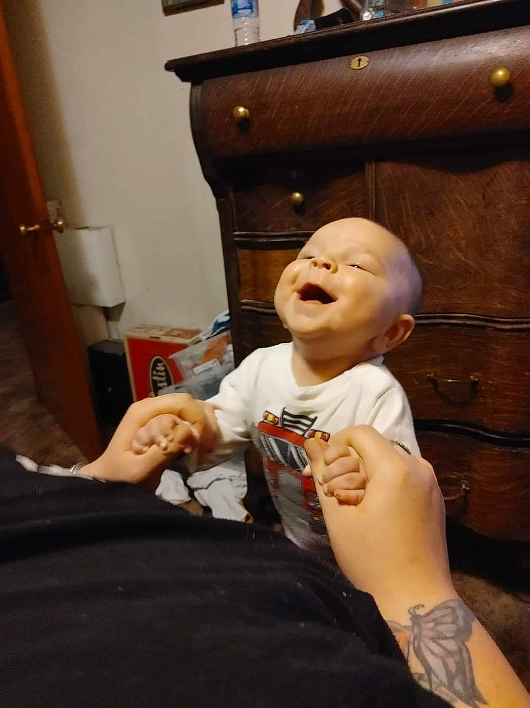 Jaxon is registered to the contest to win money with this photo: cabinetry, chest_of_drawers, child, comfort, drawer, elbow, event, finger, fun, gesture, happy, human_leg, nail, person, room, sitting, smile, thumb, toddler, wood