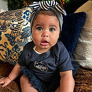 Eden is registered to the contest to win money with this photo: baby, child, infant, headband, striped, blue_clothing, sitting, blanket, pillow, patterned_pillow, indoor, curious_expression, big_eyes, cute, soft_lighting, portrait, young_child, toddler, cozy, home