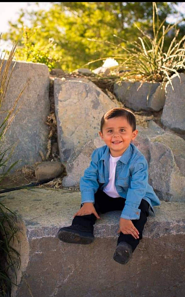 Emilio is registered to the contest to win money with this photo: eye, footwear, grass, hair, hairstyle, happy, head, human_body, joy, landscape, leg, leisure, people_in_nature, person, plant, shoe, smile, temple, toddler, tree