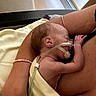 Ella is registered to the contest to win money with this photo: newborn, baby, infant, medical_tube, adult_arm, blanket, skin, resting, indoors, closeup, care, tenderness, healthcare, hospital, person, comfort, fragile, holding, peaceful, parent