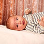 Basile participe au concours pour gagner de l'argent avec cette photo : baby, infant, child, face, eyes, hand, blanket, clothing, striped_sweater, portrait, indoor, soft_lighting, curious, lying_down, warm_colors, background, decor, skin, expression, young