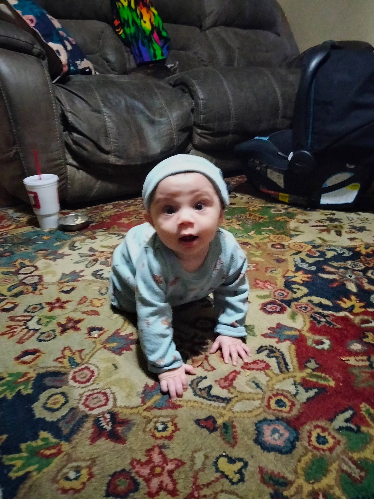 Cash is registered to the contest to win money with this photo: baby, baby_toddler_clothing, carpet, cheek, child, comfort, couch, crawling, eye, face, floor, flooring, grass, green, hardwood, head, headwear, person, room, sitting