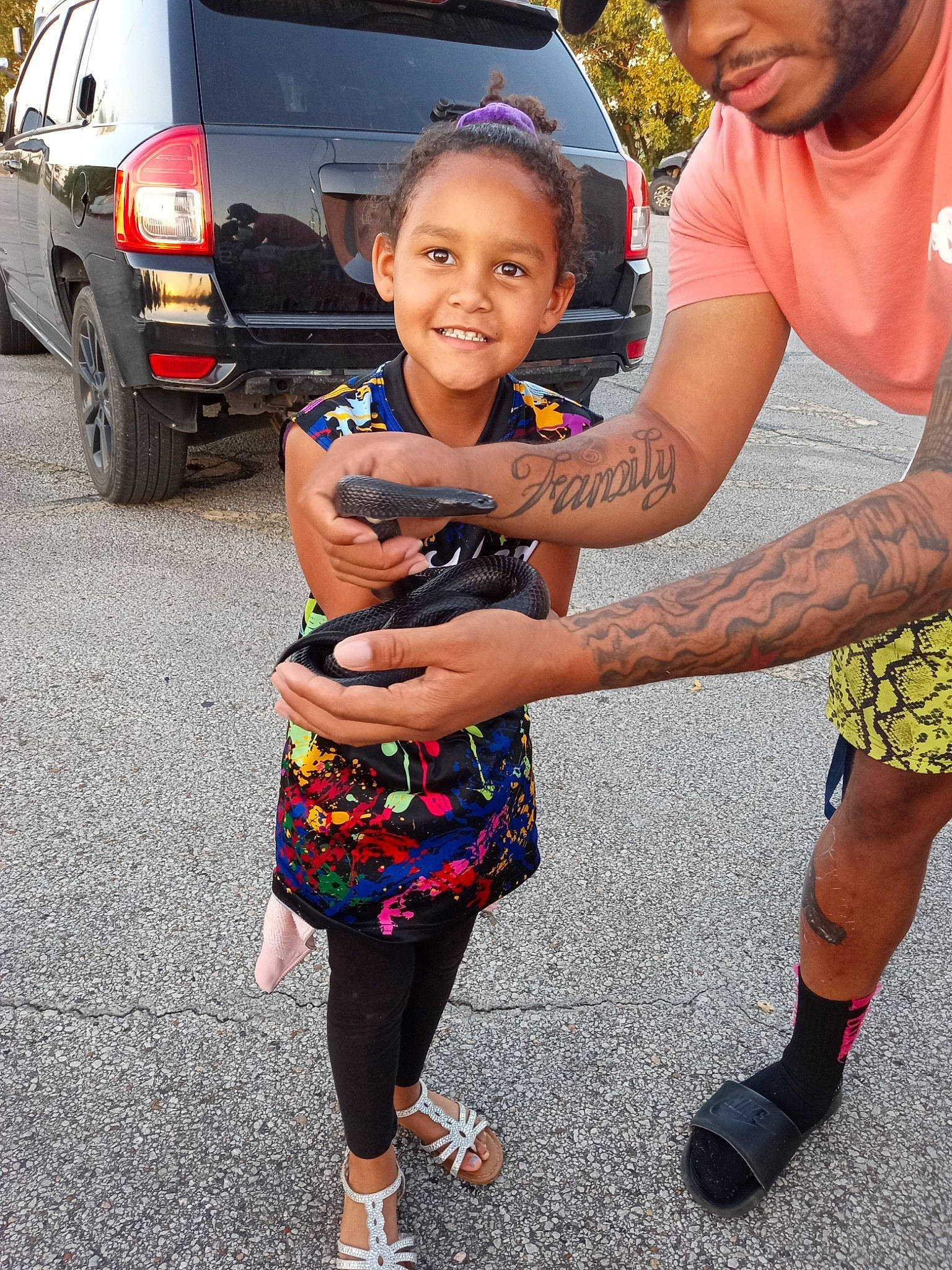 Londin is registered to the contest to win money with this photo: automotive_exterior, automotive_tire, baseball_cap, car, event, fun, gesture, happy, joy, leisure, motor_vehicle, people, person, shorts, smile, snapshot, t_shirt, tire, toddler, vehicle