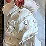 baby, sleeping, infant, pajamas, white_clothing, bear_pattern, soft_surface, changing_pad, peaceful, newborn, person, cute, cozy, lying_down, small_hands, small_feet, indoors, carpet, child, portrait