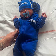 Ylann a rejoint le concours — aidez-le/la à gagner de superbes lots ! baby, bed, blue_clothing, child, cozy, footwear, hand, hat, indoor, infant, newborn, onesie, pacifier, peaceful, person, sleep, sleeping, soft, tattoo, white_sheet