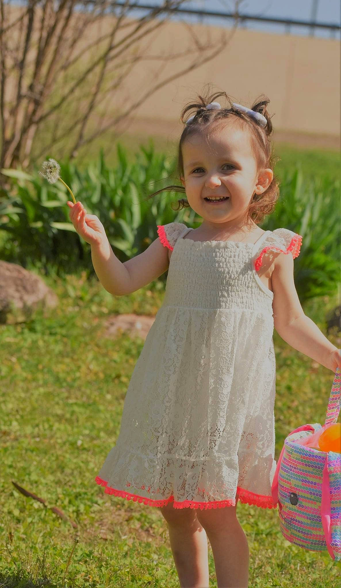 Maisie is registered to the contest to win money with this photo: baby, baby_toddler_clothing, day_dress, dress, face, gesture, grass, green, happy, joy, luggage_and_bags, one_piece_garment, people_in_nature, person, pink, plant, shoulder, skin, smile, toddler