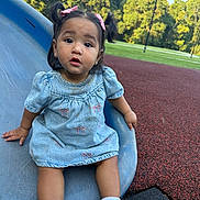 Isabella joined the competition — help win amazing prizes! casual_clothing, child, curious, cute, daylight, denim_dress, fun, grass, outdoor, park, person, pink_bows, play, playground, sitting, slide, toddler, trees, white_socks, young_child
