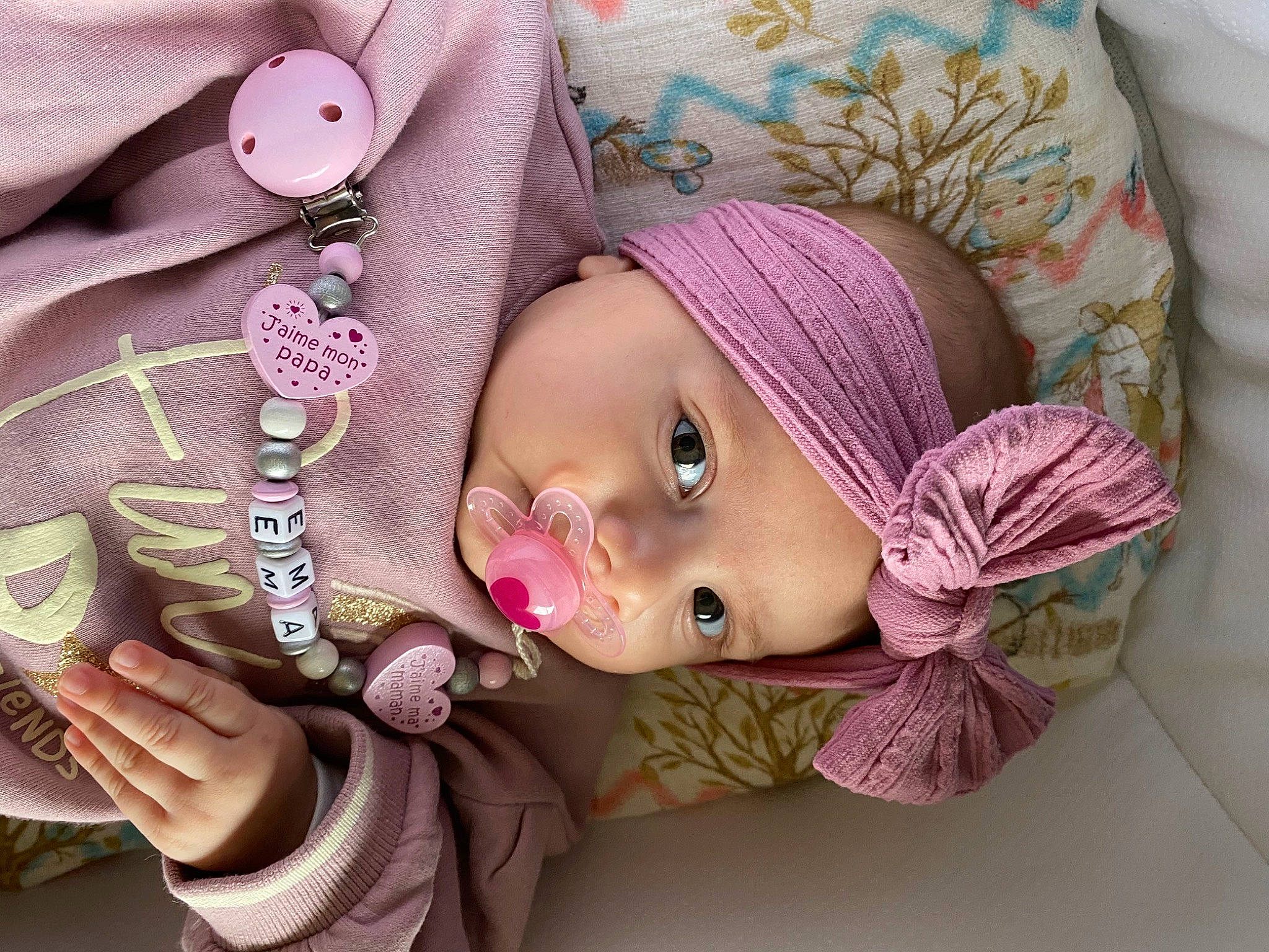 Ema participe au concours pour gagner de l'argent avec cette photo : baby, baby_toddler_clothing, cap, cheek, eye, eyelash, face, hand, head, headgear, iris, lip, mouth, nose, pink, purple, skin, sleeve, textile, violet
