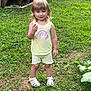 child, toddler, grass, outdoor, summer, yellow_clothing, unicorn_print, rainbow, sandals, greenery, garden, plant, nature, smiling, standing, shorts, tank_top, cute, happy, person