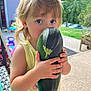 child, toddler, vegetable, zucchini, outdoor, green, summer, curious, holding, garden, nature, play, cute, person, portrait, daylight, casual, blonde, yellow_shirt, closeup