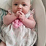 Ella is registered to the contest to win money with this photo: baby, infant, child, dress, flower, hands, face, cushion, seat, pattern, pink, white, gray, skin, cute, portrait, sitting, indoors, soft, clothing