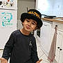Naël participe au concours pour gagner de l'argent avec cette photo : child, boy, halloween_hat, kitchen, tile_floor, blue_pants, black_shirt, playful, expression, fridge, drawing, cabinet, dishwasher, towel, indoor, person, curly_hair, smile, hands, home