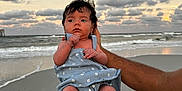 Aurora is registered to the contest to win money with this photo: baby, beach, child, clouds, cute, dress, hands, holding, infant, nature, ocean, outdoor, person, portrait, sand, shore, sky, sunset, water, waves