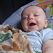 Parker is registered to the contest to win money with this photo: baby, infant, child, smiling, laughing, portrait, lying_down, bed, blanket, bedding, nursery, indoor, cozy, face, eyes, mouth, onesie, colorful, phone_screenshot, gallery_interface
