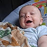 baby, infant, child, smiling, laughing, portrait, lying_down, bed, blanket, bedding, nursery, indoor, cozy, face, eyes, mouth, onesie, colorful, phone_screenshot, gallery_interface