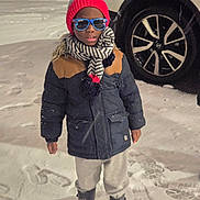 Nathaniel is registered to the contest to win money with this photo: child, snow, winter_clothing, beanie, scarf, sunglasses, boots, car, toddler, outdoor, cold_weather, footprints, jacket, pants, standing, night, street, urban, person, fashion