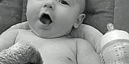 Kolten is registered to the contest to win money with this photo: baby, infant, blanket, baby_bottle, seat, cushion, face, mouth_open, skin, arm, head, child, monochrome, indoor, comfort, expression, soft_texture, newborn, relaxing, portrait