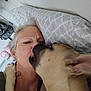 affection, animal, bedroom, casual, closeup, comfort, dog, expression, face, furniture, human, indoor, licking, love, pet, pillow, resting, skin, tattoo, woman