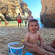 Abel participe au concours pour gagner de l'argent avec cette photo : toddler, child, beach, sand, bucket, toy, smiling, sunny, water, rocks, cliffs, people, swimming, summer, vacation, play, happy, family, outdoor, hat