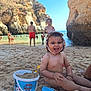 toddler, child, beach, sand, bucket, toy, smiling, sunny, water, rocks, cliffs, people, swimming, summer, vacation, play, happy, family, outdoor, hat