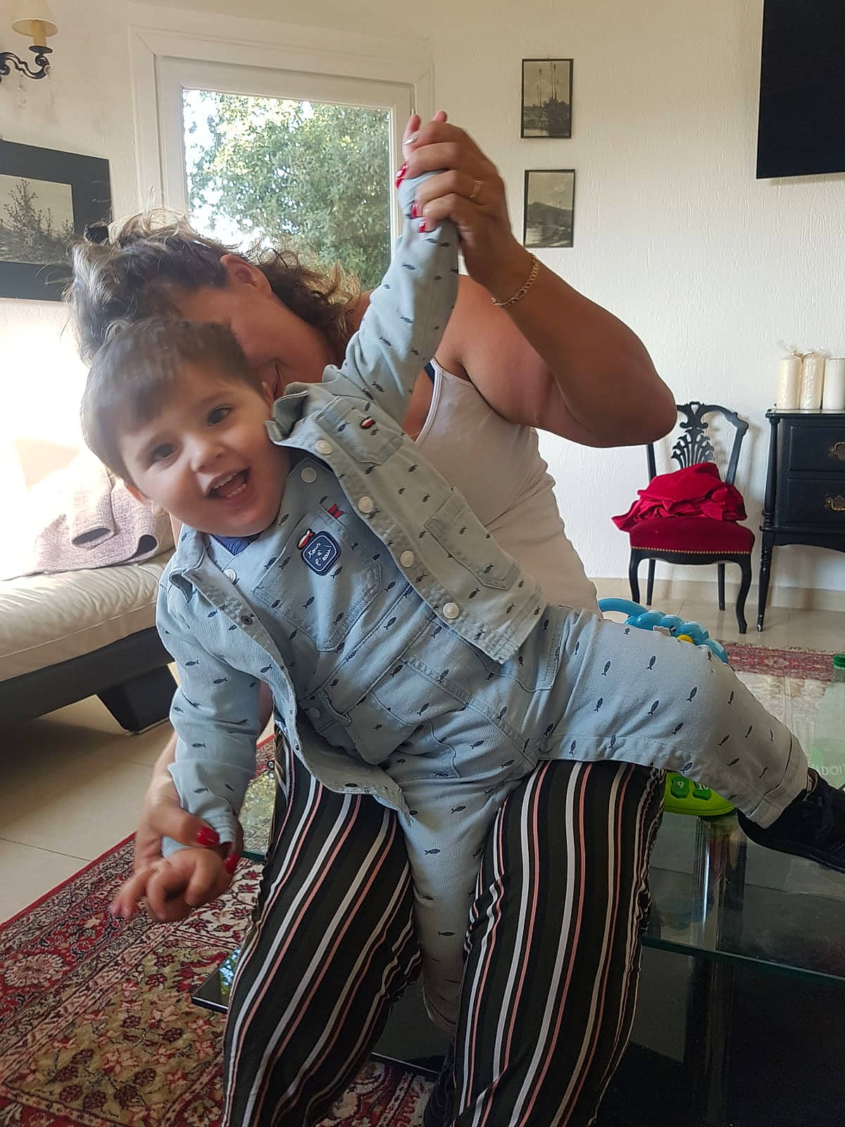 Tino a rejoint le concours — aidez-le/la à gagner de superbes lots ! barefoot, chair, child, comfort, couch, flooring, fun, gesture, happy, houseplant, joint, lamp, person, picture_frame, shoulder, sitting, sleeve, smile, thigh, toddler