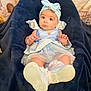 baby, child, blue_dress, headband, bow, blanket, footwear, white_booties, lace_socks, cute, portrait, indoor, soft_texture, curious_expression, small_hands, infant, comfortable, looking_at_camera, seated, adorable