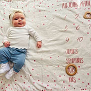 Maddy participe au concours pour gagner de l'argent avec cette photo : baby, infant, child, blanket, headband, white_top, blue_pants, white_shoes, star_pattern, wooden_ring, milestone, age_marker, lying_down, smile, portrait, indoors, cute, baby_photo, soft_lighting, head