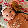 Maddy participe au concours pour gagner de l'argent avec cette photo : baby, infant, headband, plush_toy, elephant, clothing, text_on_clothing, blanket, patterned_blanket, closeup, face, cute, soft_lighting, indoors, child, portrait, lying_down, pink, brown, cozy