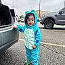 accessory, asphalt, car, child, clothing, costume, curious, cute, footwear, glasses, holding, outdoor, overcast, parking_lot, person, standing, toddler, toy_shoes, vehicle, winter_wear