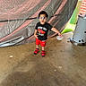 Dwayne is registered to the contest to win money with this photo: black_tshirt, boy, casual, child, clothing, concrete_floor, curious, daylight, garage, goggles, metallic_object, outdoor, person, playful, red_shoes, red_shorts, short_hair, standing, tarp, trash_bin
