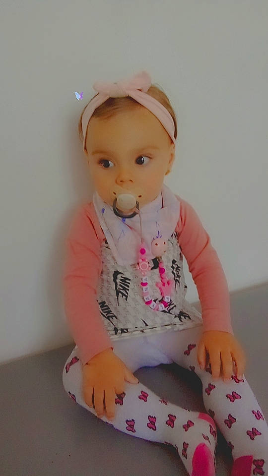 Elyana participe au concours pour gagner de l'argent avec cette photo : baby, baby_products, baby_toddler_clothing, cap, cheek, child, face, fashion_accessory, knee, leggings, magenta, pattern, peach, person, pink, sitting, sleeve, sock, t_shirt, thigh