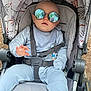 baby, stroller, sunglasses, reflection, child, outdoor, person_reflection, blue_clothing, seatbelt, infant, sun_glasses, baby_boy, casual, relaxed, baby_seat, baby_accessory, daylight, fashion, cute, portrait