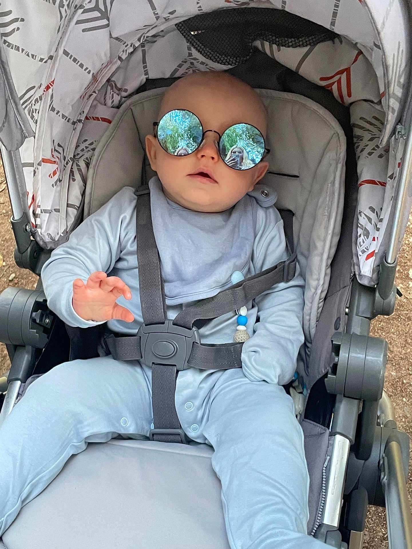 Anakin is registered to the contest to win money with this photo: baby, stroller, sunglasses, reflection, child, outdoor, person_reflection, blue_clothing, seatbelt, infant, sun_glasses, baby_boy, casual, relaxed, baby_seat, baby_accessory, daylight, fashion, cute, portrait