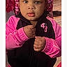 Tori Jones is registered to the contest to win money with this photo: child, toddler, girl, pink_clothing, black_clothing, braided_hair, beads, indoor, person, portrait, curious_expression, jacket, hands, face, young, cute, standing, clothing, human, closeup