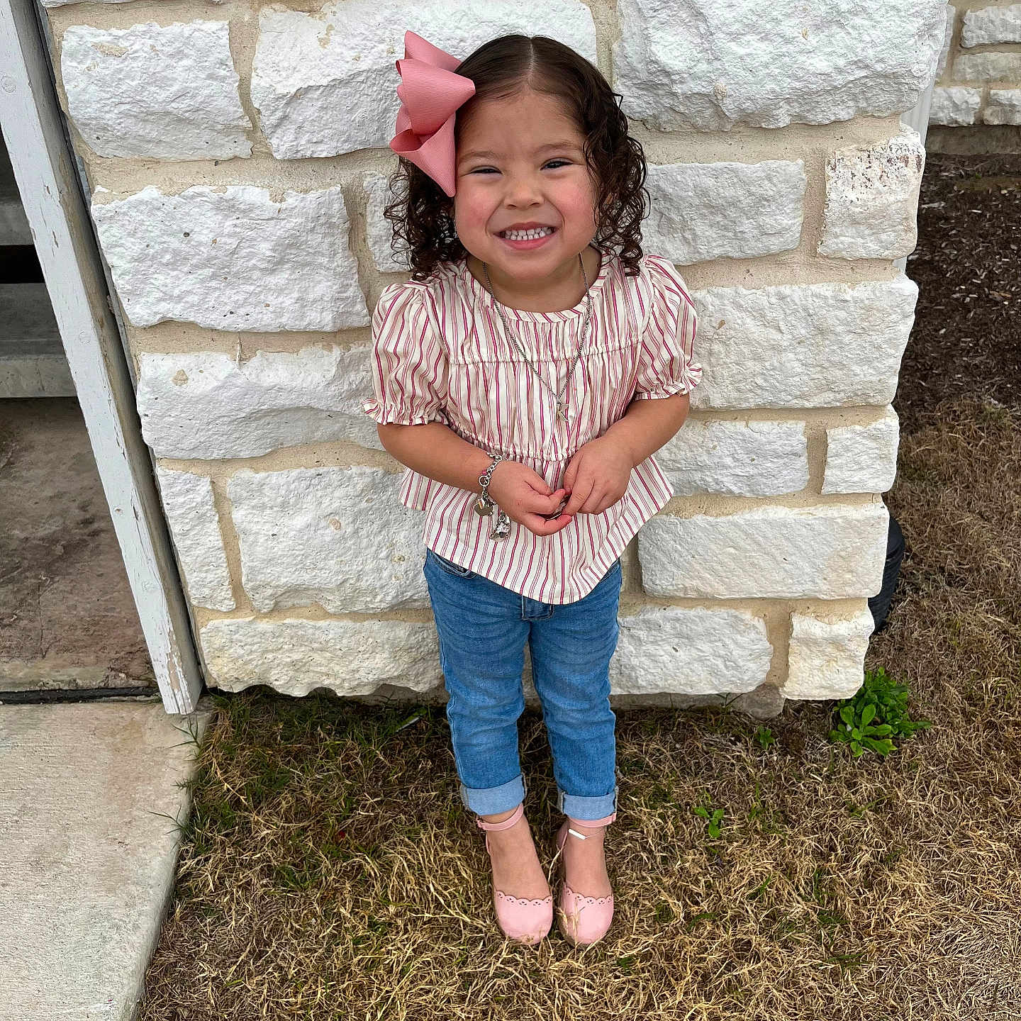 Kaliyah is registered to the contest to win money with this photo: architecture, building, child, clothing, face, female, girl, grass, happy, head, jeans, pants, person, photography, plant, portrait, rock, smile, standing, wall