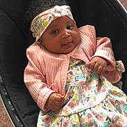 Rahnearah is registered to the contest to win money with this photo: baby, infant, child, headband, pink_jacket, floral_dress, smiling, cute, portrait, indoors, seat, black_seat, hands, face, expression, young_child, cozy, comfortable, clothing, adorable