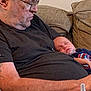 accessories, adult, baby, clothing, couch, cushion, face, furniture, glasses, head, indoors, male, man, newborn, people, person, photography, portrait, sleeping, t_shirt