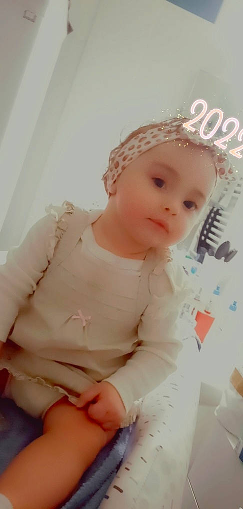 Lena a rejoint le concours — aidez-le/la à gagner de superbes lots ! baby, baby_toddler_clothing, blond, cap, cheek, chin, comfort, dress, fashion_accessory, happy, headpiece, human_leg, knee, lip, person, pink, skin, sleeve, smile, thigh