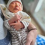 baby, newborn, sleeping, infant, striped_clothing, hat, bib, hand, adult_arm, holding, cozy, soft_light, indoor, portrait, peaceful, human, closeup, skin, person, calm