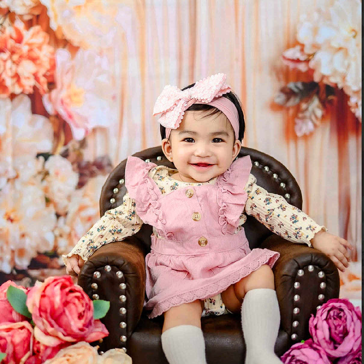 Francheska Dior is registered to the contest to win money with this photo: armchair, baby, child, cute, decor, fashion, floral_background, flowers, happy, headband, indoor, person, pink_bow, pink_dress, portrait, seated, smiling, studio_photo, toddler, white_socks
