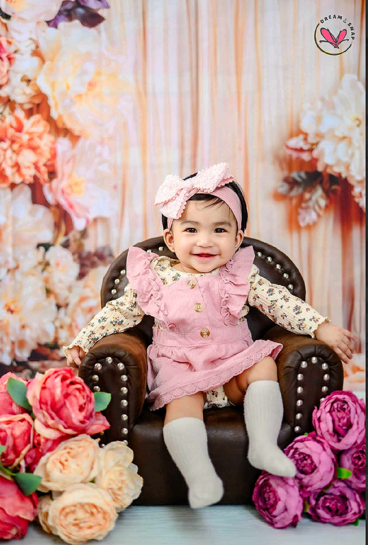 Francheska Dior is registered to the contest to win money with this photo: baby, child, smiling, pink_bow, headband, pink_dress, armchair, flowers, floral_background, white_socks, portrait, cute, indoor, happy, person, toddler, decor, seated, studio_photo, fashion