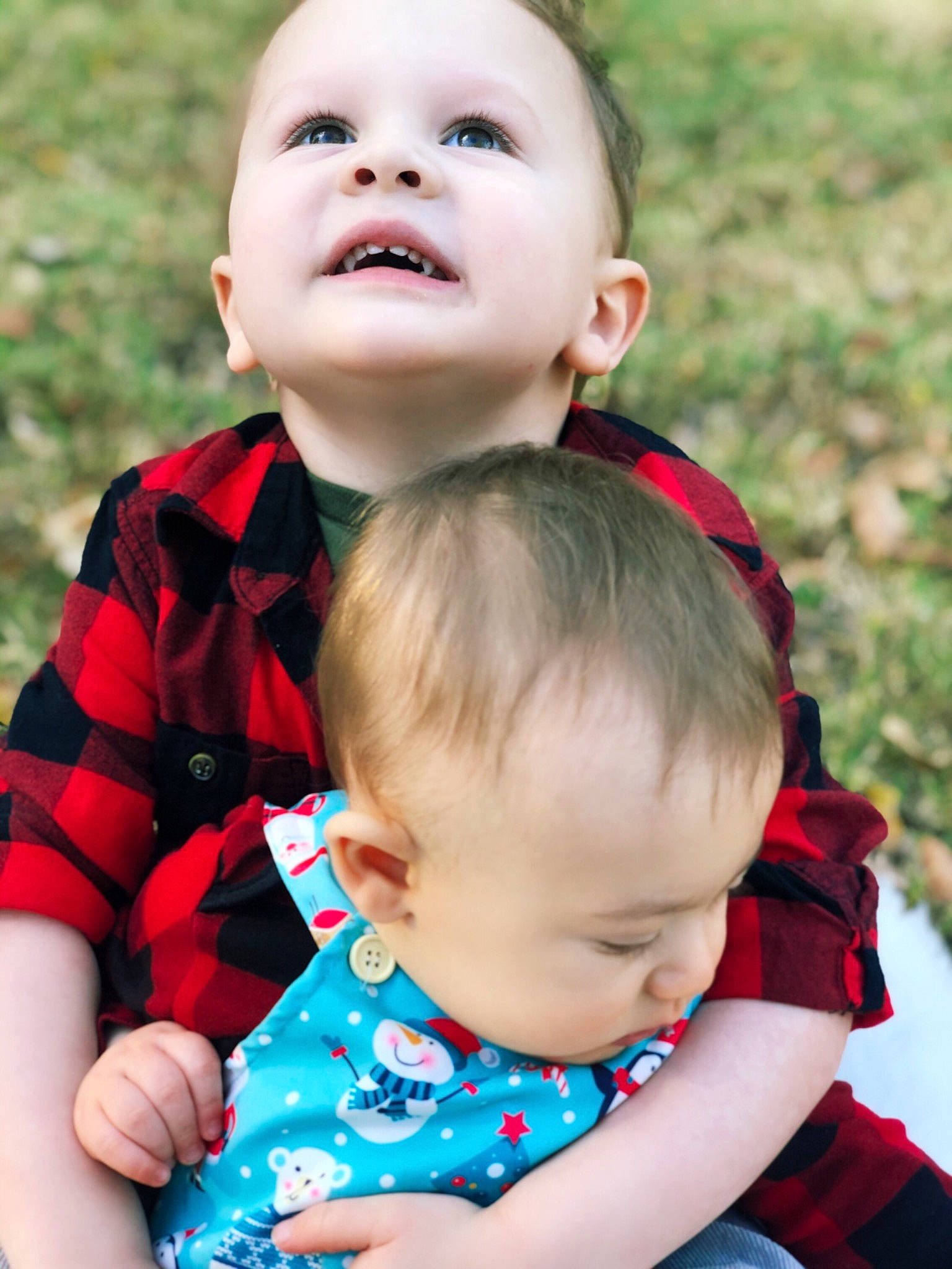 Teegan is registered to the contest to win money with this photo: baby, baby_toddler_clothing, cheek, child, child_model, design, face, grass, happy, lip, pattern, people_in_nature, person, photography, plaid, playing_with_kids, portrait_photography, red, sibling, skin