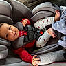 Lennox is registered to the contest to win money with this photo: baby, car_seat, child, smiling, red_shirt, gray_pants, blanket, arrow_pattern, infant, safety_harness, happy, indoors, seat_belt, cute, person, foot, hand, clothing, car_interior, portrait