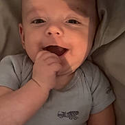 Colson is registered to the contest to win money with this photo: baby, infant, smiling, hand, onesie, clothing, face, cute, child, lying_down, happy, skin, person, young_child, expression, indoors, soft_light, closeup, cheerful, playful