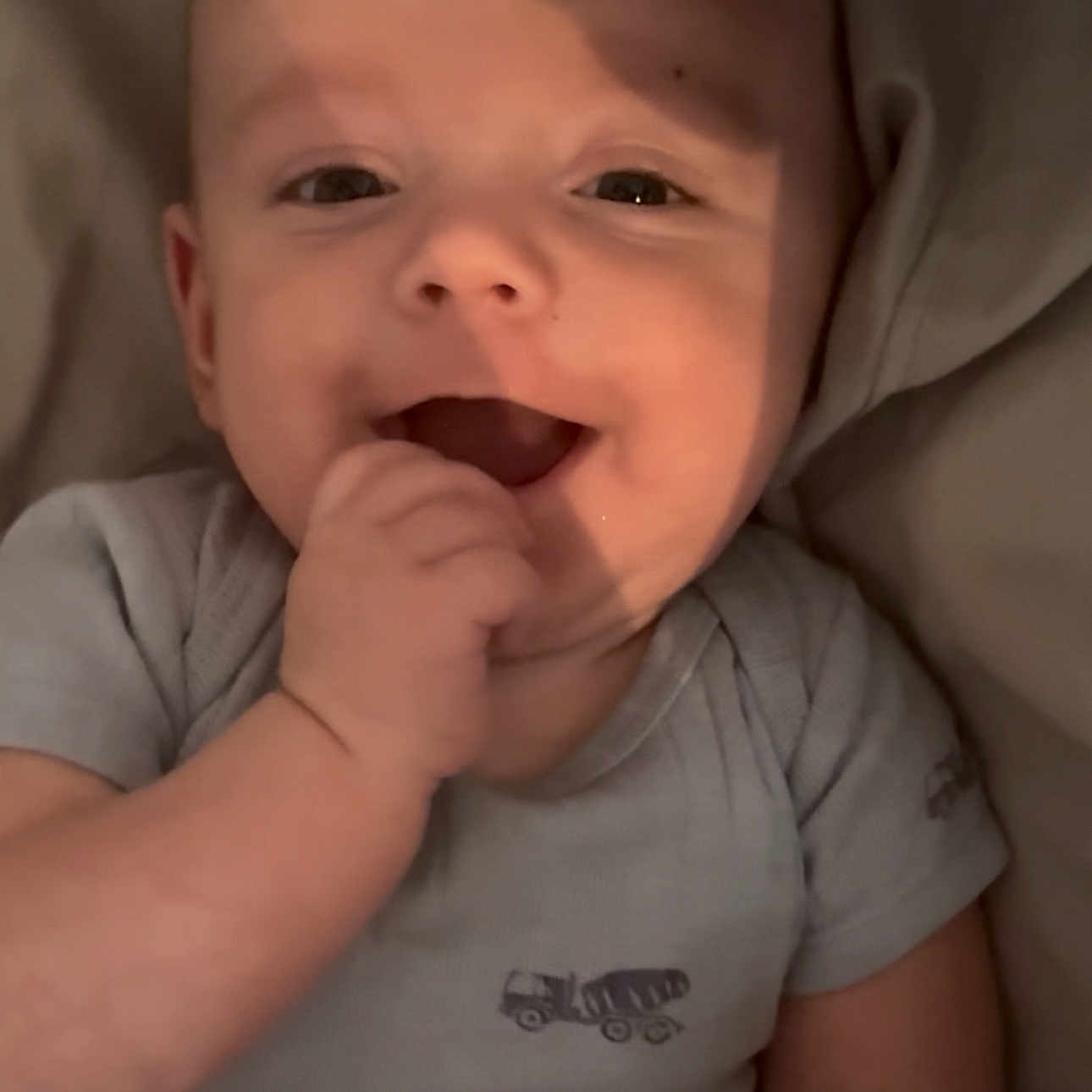 Colson is registered to the contest to win money with this photo: baby, cheerful, child, closeup, clothing, cute, expression, face, hand, happy, indoors, infant, lying_down, onesie, person, playful, skin, smiling, soft_light, young_child