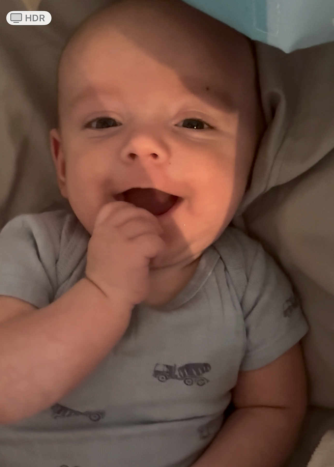 Colson is registered to the contest to win money with this photo: baby, infant, smiling, hand, onesie, clothing, face, cute, child, lying_down, happy, skin, person, young_child, expression, indoors, soft_light, closeup, cheerful, playful
