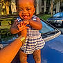 Star joined the competition — help win amazing prizes! toddler, child, smile, happy, outdoor, sunlight, car, blue_romper, brown_shoes, hand, person, face, curly_hair, holding, vehicle, hood, nature, tree, building, daylight