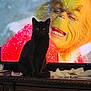 black_cat, cat, television, grinch, holiday, christmas, animal, pet, feline, darker, sitting, furniture, wooden_dresser, indoors, screen, expression, face, tissues, decor, contrast